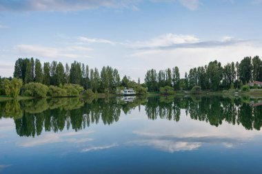 Dağın yakınında bulutların ve ormanın yansımasıyla donuk bir yaz manzarası. Issyk kul, Kırgızistan.