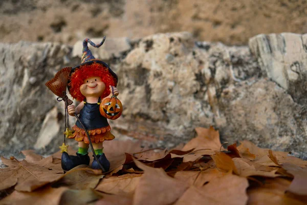 Süpürgeyle şapkalı, elinde balkabağı olan kızıl saçlı neşeli bir cadı.