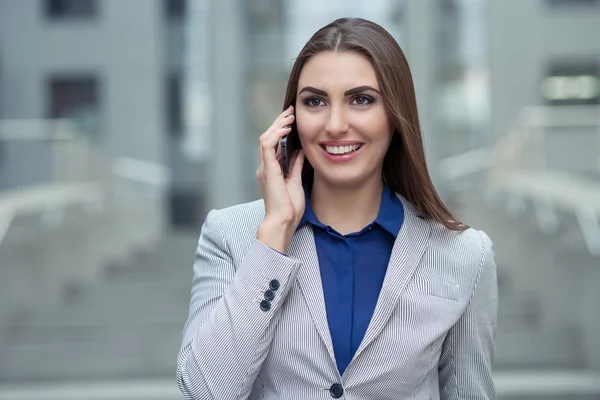 Business woman talking on a cell phone on the background of the — Stock Photo, Image