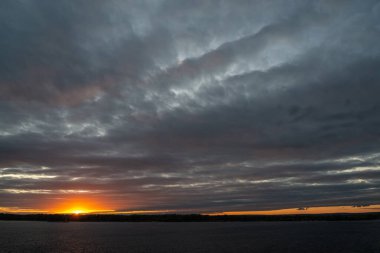 Güneşin bulutlu gökyüzünde ilk sonbahar günbatımı