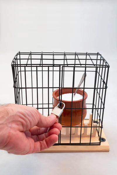 hand opening or closing the lock on a cage with a sugar jar inside, weight loss, sugar-free diet