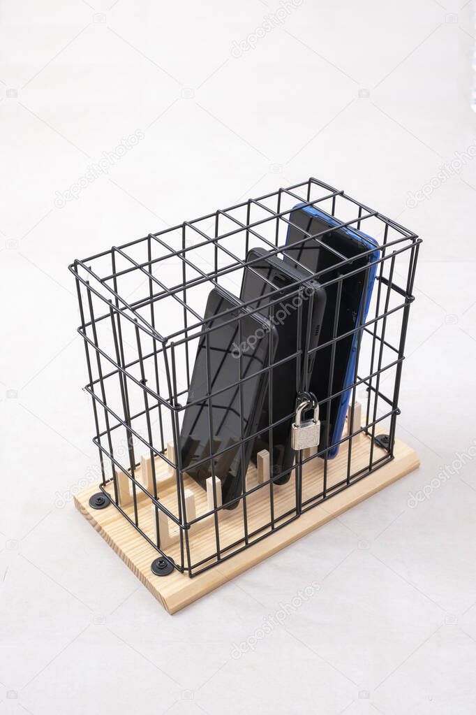 three mobile phones locked in a cage with a padlock, concept of social isolation or phone abuse and social networks, white background, vertical