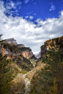 Güneşli bir günde içinden bir nehrin aktığı dağ manzarası pamuk bulutları, Bellos nehri Anisclo kanyonu, Huesca Pirenes, İspanya