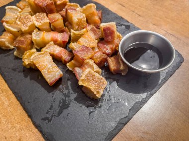 Bir tabak kızarmış torreznos ya da siyah bir tabakta kızarmış pastırma ve barbekü soslu bir kavanoz ya da ahşap bir masada soya sosu, İspanyol tapas.