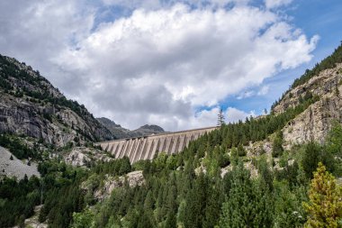 Süvariler aşağıdan bulutlu bir gökyüzü, Lleida, İspanya 'daki Pireneler' de hidroelektrik santrali ve yatay olarak görülebilen bir baraj gölü görüyorlar.