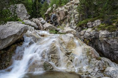 Kayalar, Noguera de Tor nehri, Boi Vadisi 'nde, İspanya' nın başkenti Lleida 'daki Pireneler' de bulunan süvari barajı arasında akan yüksek bir nehirde küçük bir şelale.
