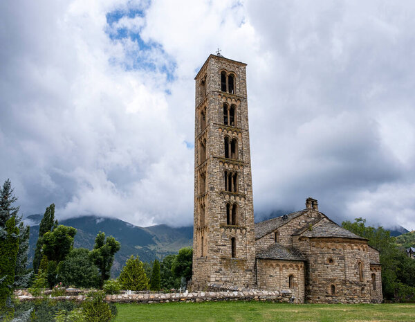 Romanesque church of San Clemente of Tahull, with its high bell tower and the mountains of the Lleida Pyrenees in the background on a cloudy day, horizontal