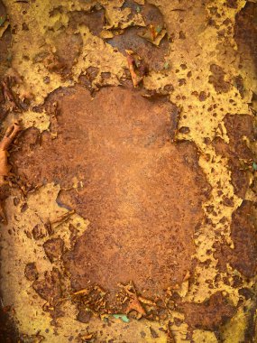 Close-up of rusty metal with peeling yellow paint, showing texture, decay, and corrosion in an abstract industrial surface background, vertical