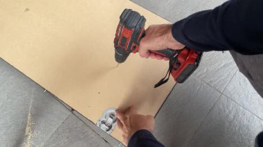 Kablosuz matkabı kapat. Masanın üstünde, yatay bir şekilde tahta bir tahtada delik aç.