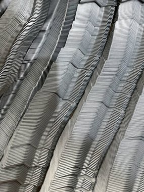 Yığılmış metal parantezler, güçlü çizgiler, dokular ve endüstriyel soyut bir görünüme sahip tekrarlayan geometrik desenler oluşturuyor.