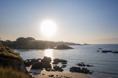 Sakin dalgalar ve sıcak ışığın yansıdığı kayalık bir sahil şeridinde gün batımı, İspanya 'nın Asturias kentindeki Porcia sahilinde huzurlu ve manzaralı bir kıyı manzarası yaratıyor.