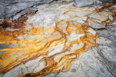 Turuncu demir oksit damarları ve gri tabaka katmanları, soyut jeolojik şablon, doku ve arkaplan ile doğal kaya dokusunun ayrıntılı yakın çekimi