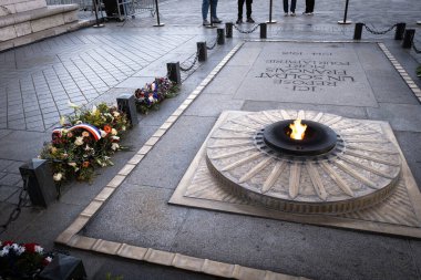 Paris 'teki Arc de Triomphe' deki bilinmeyen askerin mezarının yüksek açılı görüntüsü. Ebedi alevler yanıyor ve Fransız kurdeleleri gri bir taş kaldırımda yatay bir şekilde duruyor.