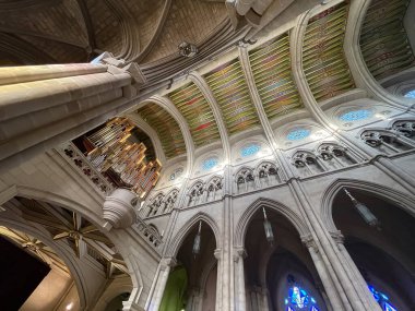 Üst iç görünüş tavan kemerlerine bakıyor ve Madrid İspanya 'daki Gotik almudena katedralinin içinde renkli geometrik desenler ve boyalı camlar içeren büyük bir boru organı var.