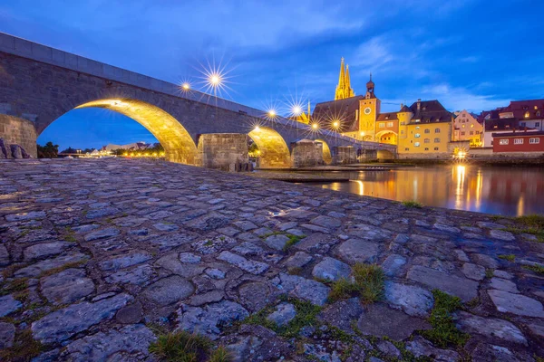 Regensburg. Ponte de pedra velha sobre o rio Danúbio à luz da noite. — Fotografia de Stock