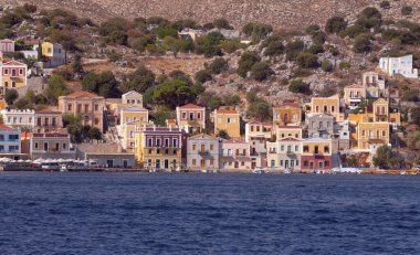 Geleneksel renkli evler, Yunanistan 'ın Suriye adasındaki yamaçta deniz ve dağlar manzaralı.
