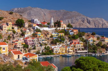 Geleneksel renkli evler, Yunanistan 'ın Suriye adasındaki yamaçta deniz ve dağlar manzaralı.