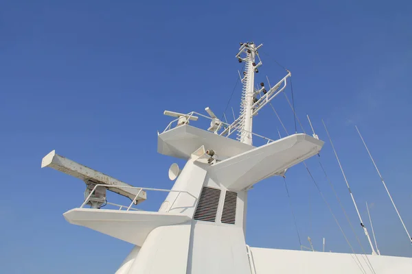 The white mast of a cruise ship with navigation equipment, radar, horns and blue-sky copy space.