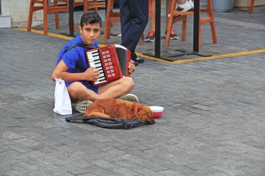 Heraklion, Girit, Yunanistan 20 Ekim 2018: Genç bir müzisyen ve köpeği Girit, Yunanistan 'da Heraklion, Girit' te bir kafe yakınlarında sokakta akordeon çalıyorlar.