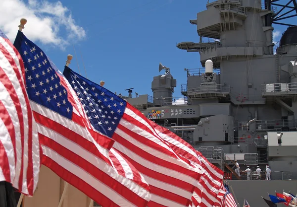 Bandeiras dos EUA voando ao lado do Battleship Missouri Memorial, com quatro marinheiros — Fotografia de Stock