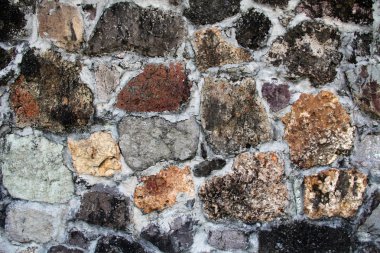 Background textured wall with unusual stones of various colors, shapes, textures and sizes found in Antigua Barbuda in the Caribbean Lesser Antilles West Indies. clipart