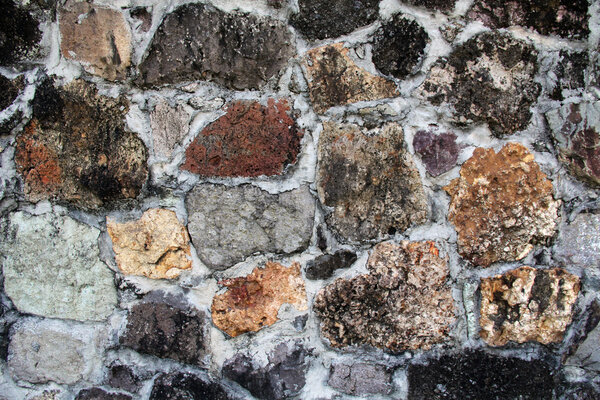 Background textured wall with unusual stones of various colors, shapes, textures and sizes found in Antigua Barbuda in the Caribbean Lesser Antilles West Indies.