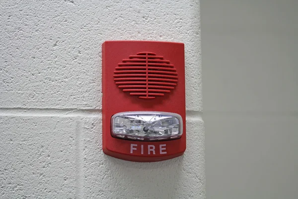 Красная пожарная сигнализация со встроенным стробоскопом для оповещения в случае пожара, расположенного на углу стены с копипространством . — стоковое фото