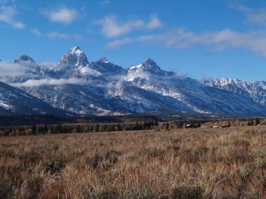 Wyoming Teton Dağları kar ve homestead çiftlik Grand Teton Milli Parkı'nda arkasında alçak bulutlar ile.
