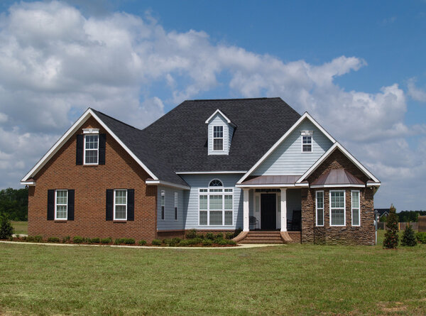 Two story residential home with brick, stone and board siding on the facade.