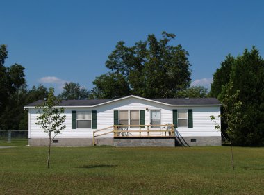 White single-wide mobile residential low income home with vinyl siding on the facade. clipart