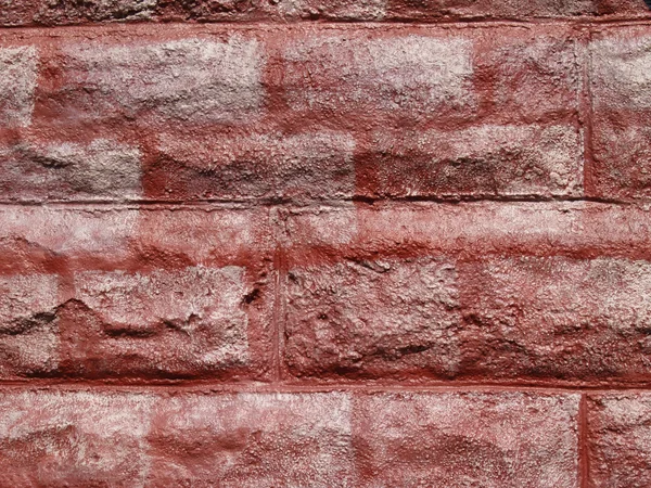 Textured concrete block wall painted to look like red bricks graffiti style.