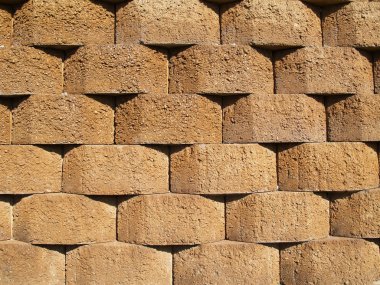 Rows of tan stone blocks that make up a retaining wall. clipart