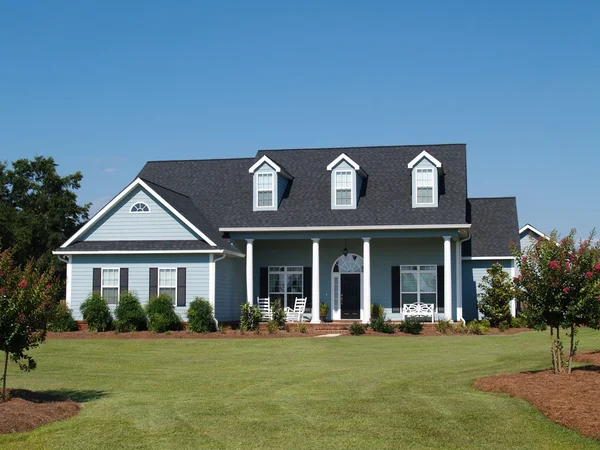 Blue two story board sided residential home with rocking chairs. — Stock Photo, Image