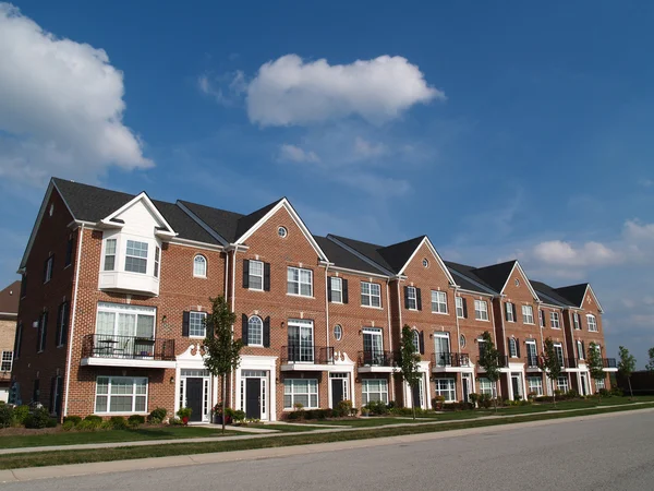 Una fila de condominios de ladrillo o casas adosadas con ventanales junto a una calle . — Foto de Stock