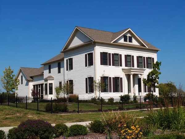 Two story new home built to look like an old historical home complete with the added on look, painted brick and a wrought  iron fence. — Stock Photo, Image