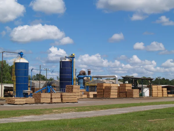 Utomståendes syn på en Sydgeorgien brädgården med blå silos och travar av färska skurna gröna lumber härdning i solskenet. — Stockfoto