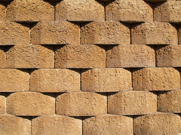 Rows of tan stone blocks that make up a retaining wall. — Stock Photo, Image