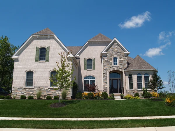 New two story white brick and stone residential home with turret and side garage. — Stock Photo, Image