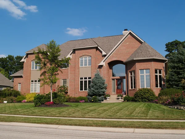 Large two story new red brick residential home with a turret at the corner. — Stock Photo, Image