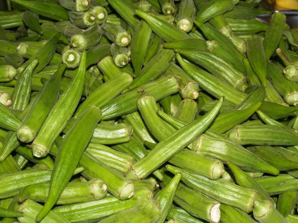 Grote stapel van verse groene okra peulen in een boerenmarkt. — Stockfoto