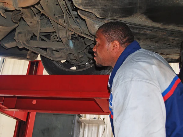 Auto mechanic performing a routine service inspection in a service garage. — Stock Photo, Image