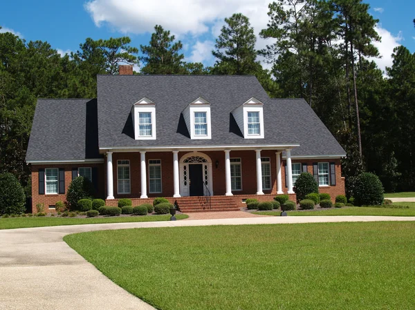 Two story brick residential home with large front porch and side entrance garage. — Stock Photo, Image