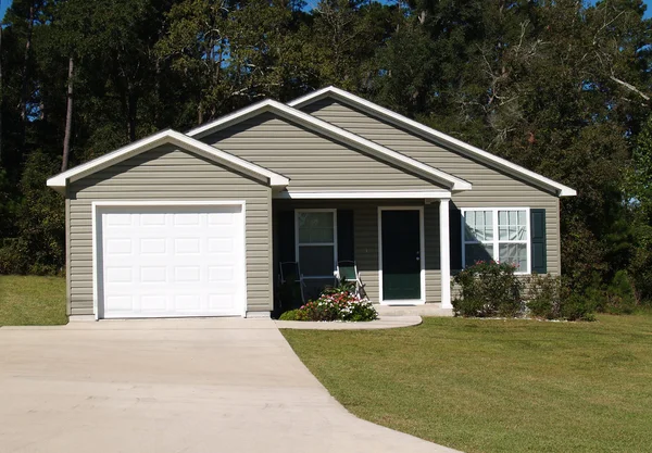 Een verhaal residentiële lage inkomen huis met grijze vinyl gevelbekleding en front entry garage. — Stockfoto
