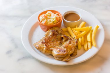 Tayland usulü karabiber soslu tavuk bifteği. Kızarmış patates, lahana salatası ve sosla servis ediliyor. Beyaz tabağa konmuş..