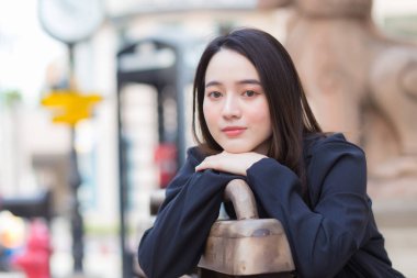 Siyah uzun kollu gömlekli güzel bir Asyalı kadının portresi. Şehrin ortasındaki koridorda bir sandalyeye otur..