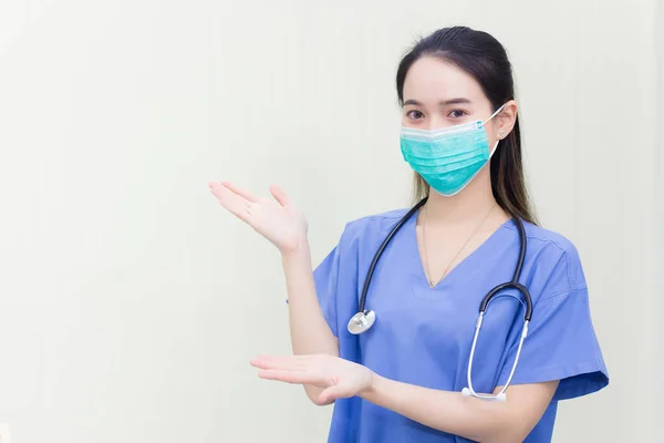 アジアの女性は 白い背景に何かを提案するために彼女の手を示している間コロナウイルス病2019 Covid の発生を保護するために医療服や医療面マスクを身に着けています — ストック写真