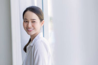 Beyaz gömlekli, uzun siyah saçlı Asyalı güzel beyaz perdeli pencerenin yanında durdu, dışarı baktı ve gülümsedi..