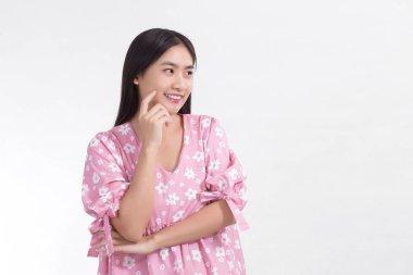 Asyalı kadın taze yüzüyle gülümser ve beyaz arka planda yüzüne dokunurken pembe elbise giyer..