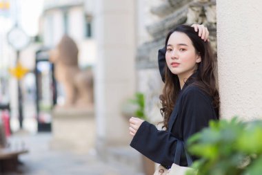 Koyu mavi cüppeli Asyalı güzel kadın dışarı bakıyor ve dışarıda bir şey bekliyor..