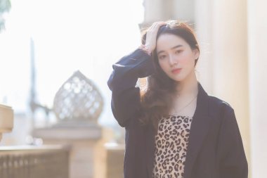 Koyu mavi takım elbiseli Asyalı güzel kadın mutlu görünüyor. Güneşli bir sabahta kahve dükkanının önünde.